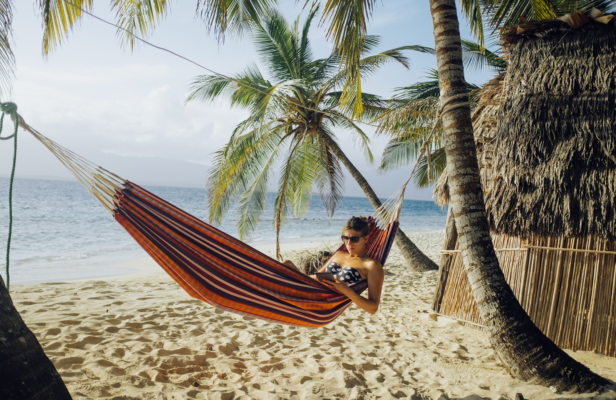 en student i ett resande klassrum i en hängmatta på en strand i costa rica