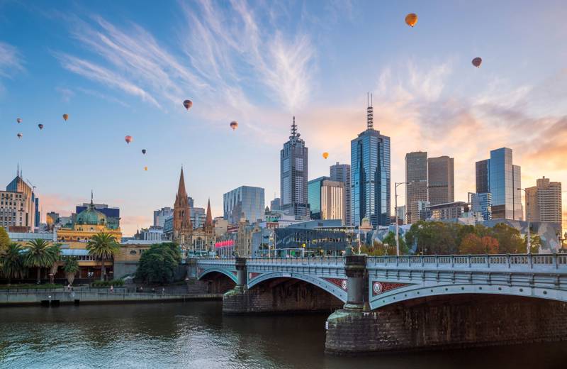 Bridge in central Melbourne, with in the background the skyline of the city and a sky filled with hot air balloons.