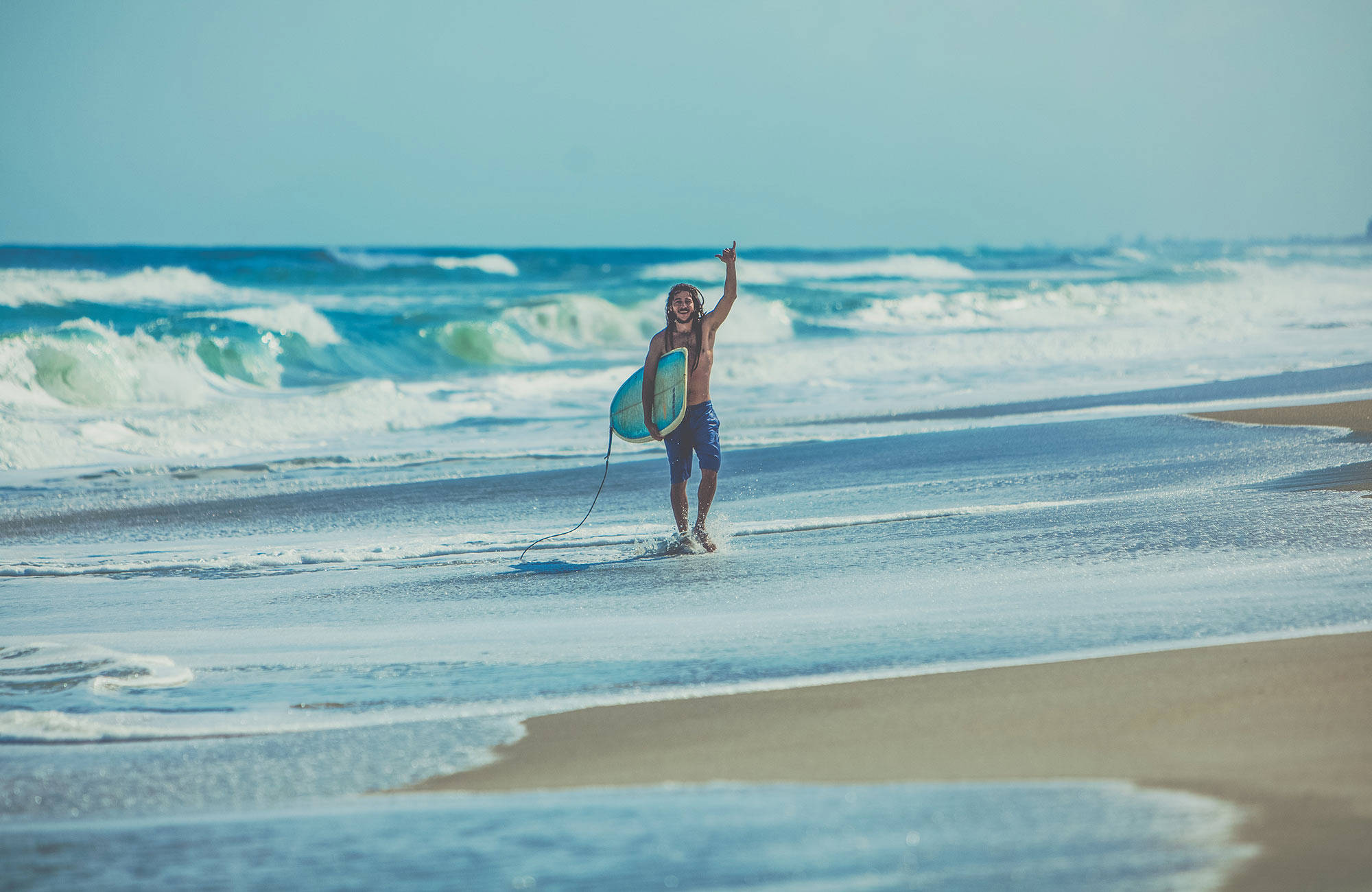 En man bär en surfingbräda på en strand i Australien