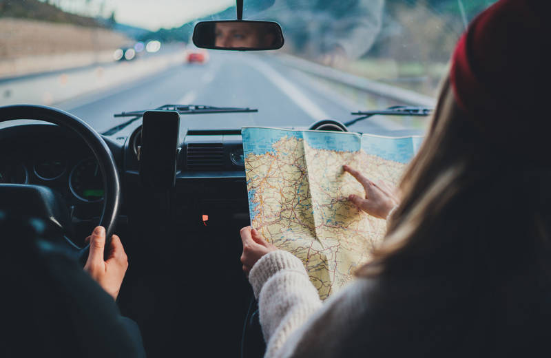 En man och en kvinna sitter i en bil och navigerar under en roadtrip i Nordamerika