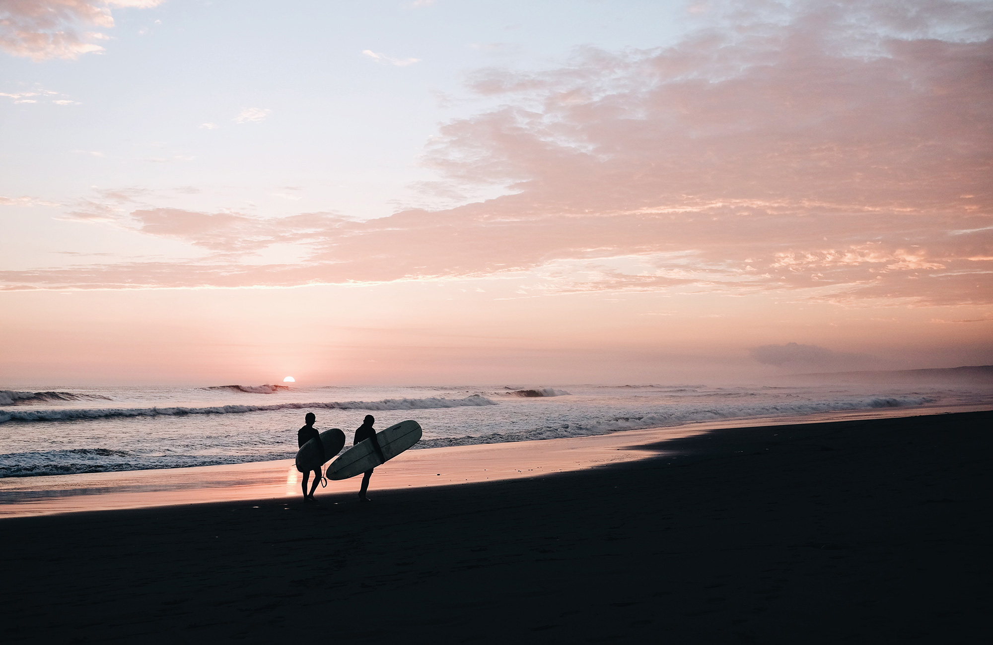 två surfare i solnedgången