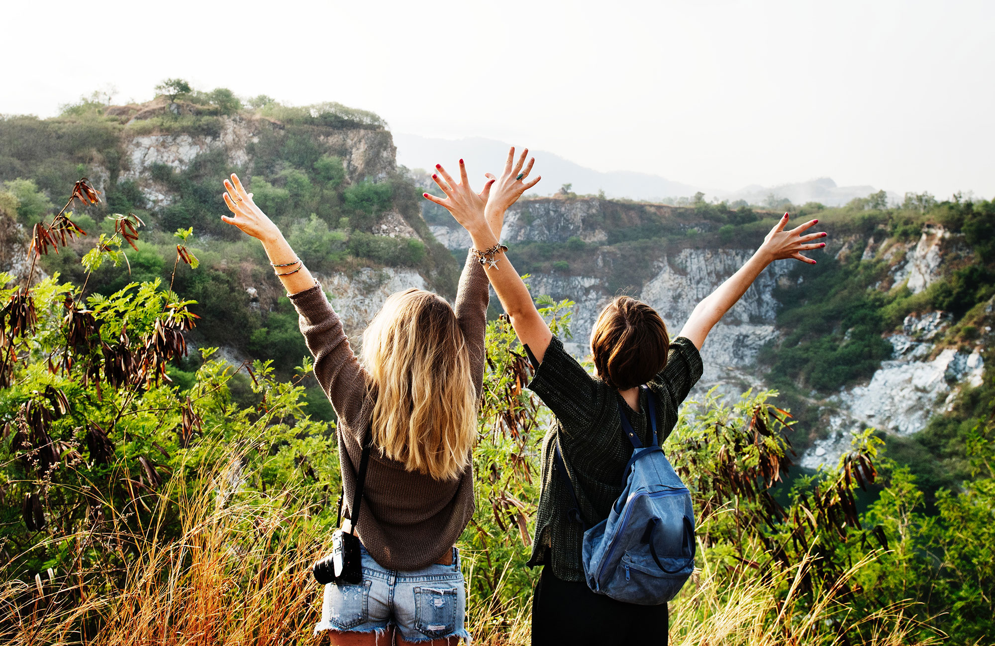 Två tjejer på hajk med utsikt över skog och berg