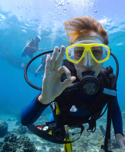 En dykare visar med tuber tar ett dykcertifikat under en dykning i Thailand