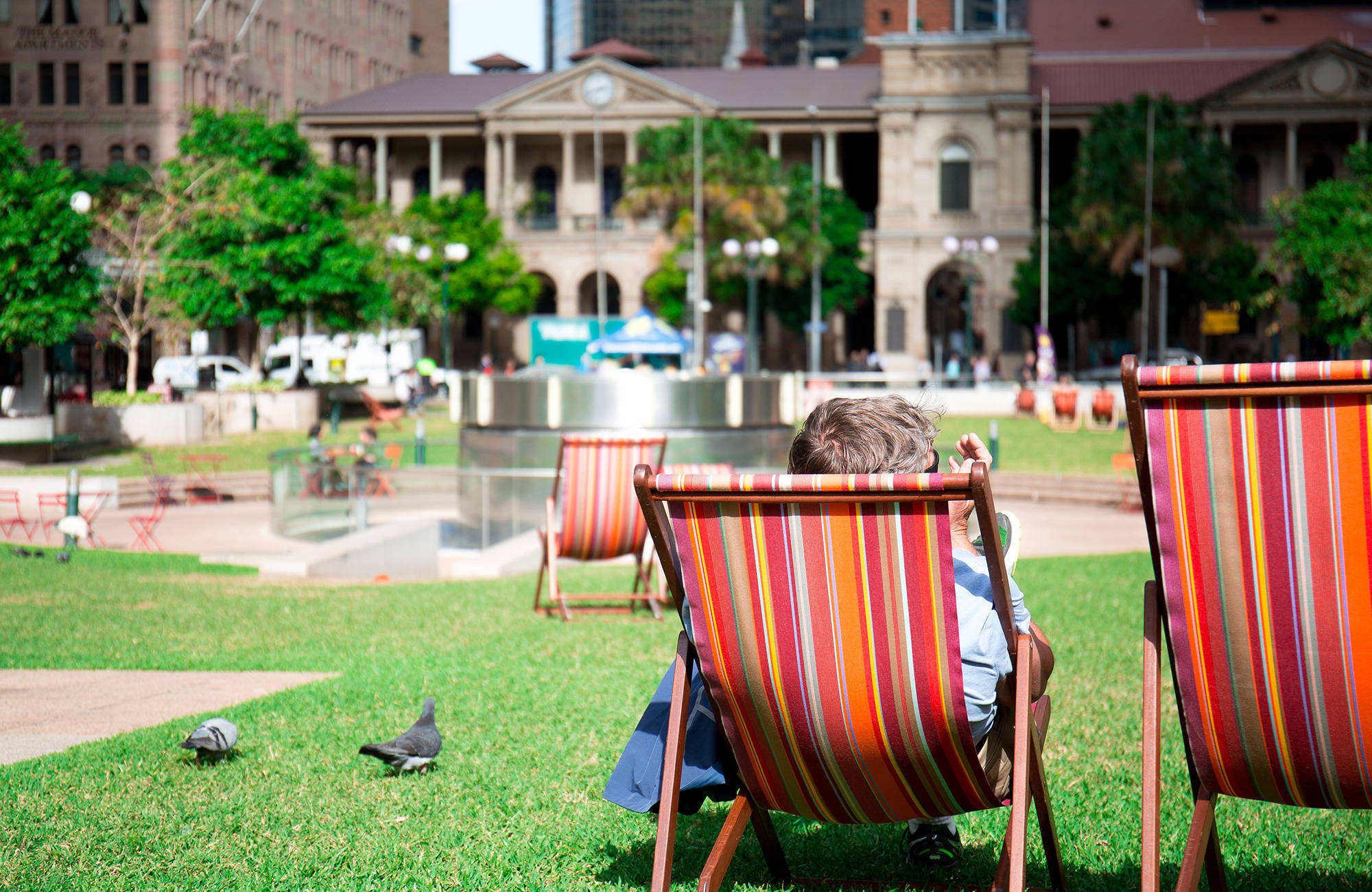 En park och en man i en röd solstol som möjligtvis studerar i Brisbane