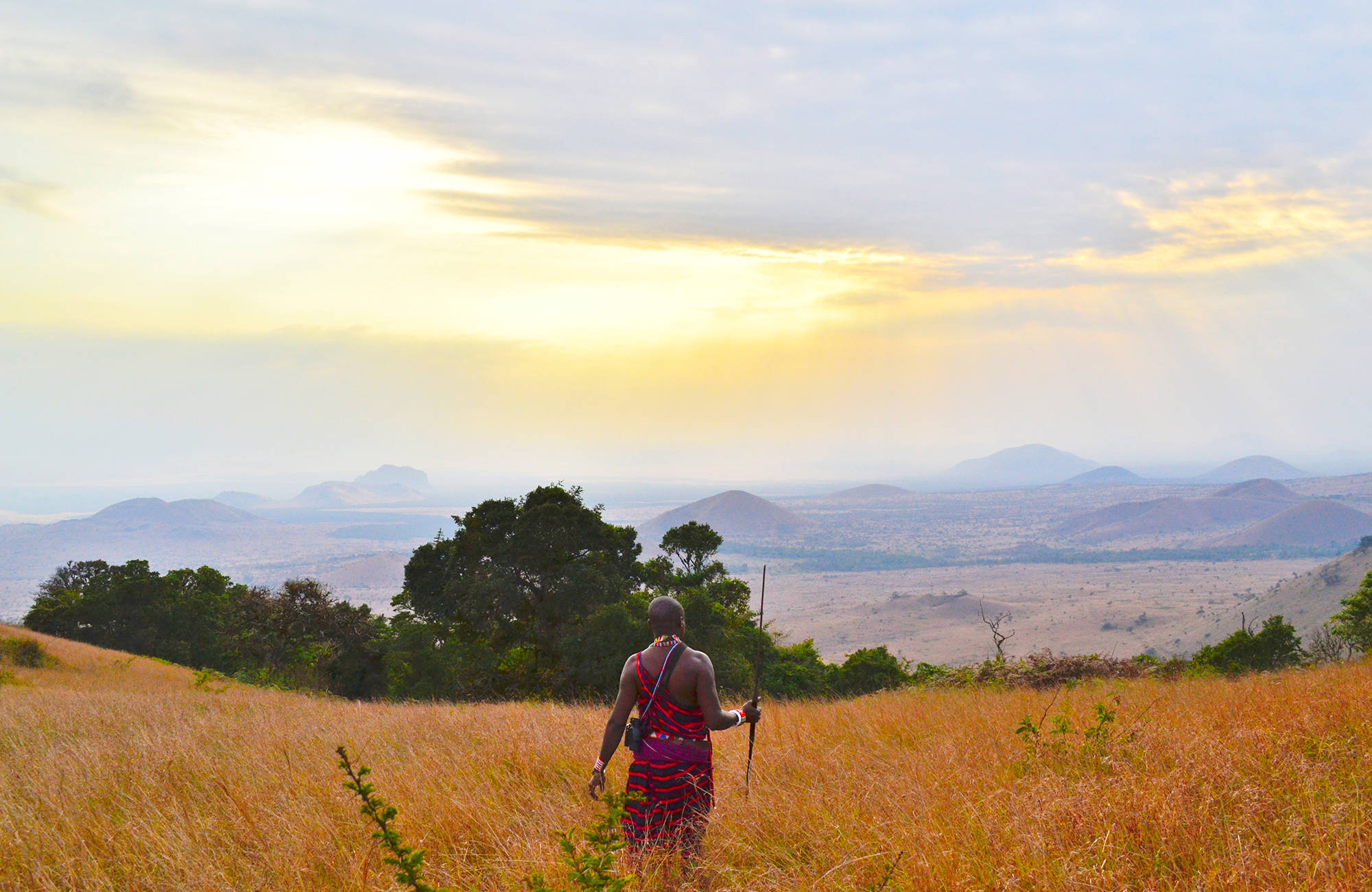 Vackert öppet lanskap och en man i traditionsenlig klädsel under en resa i Kenya.