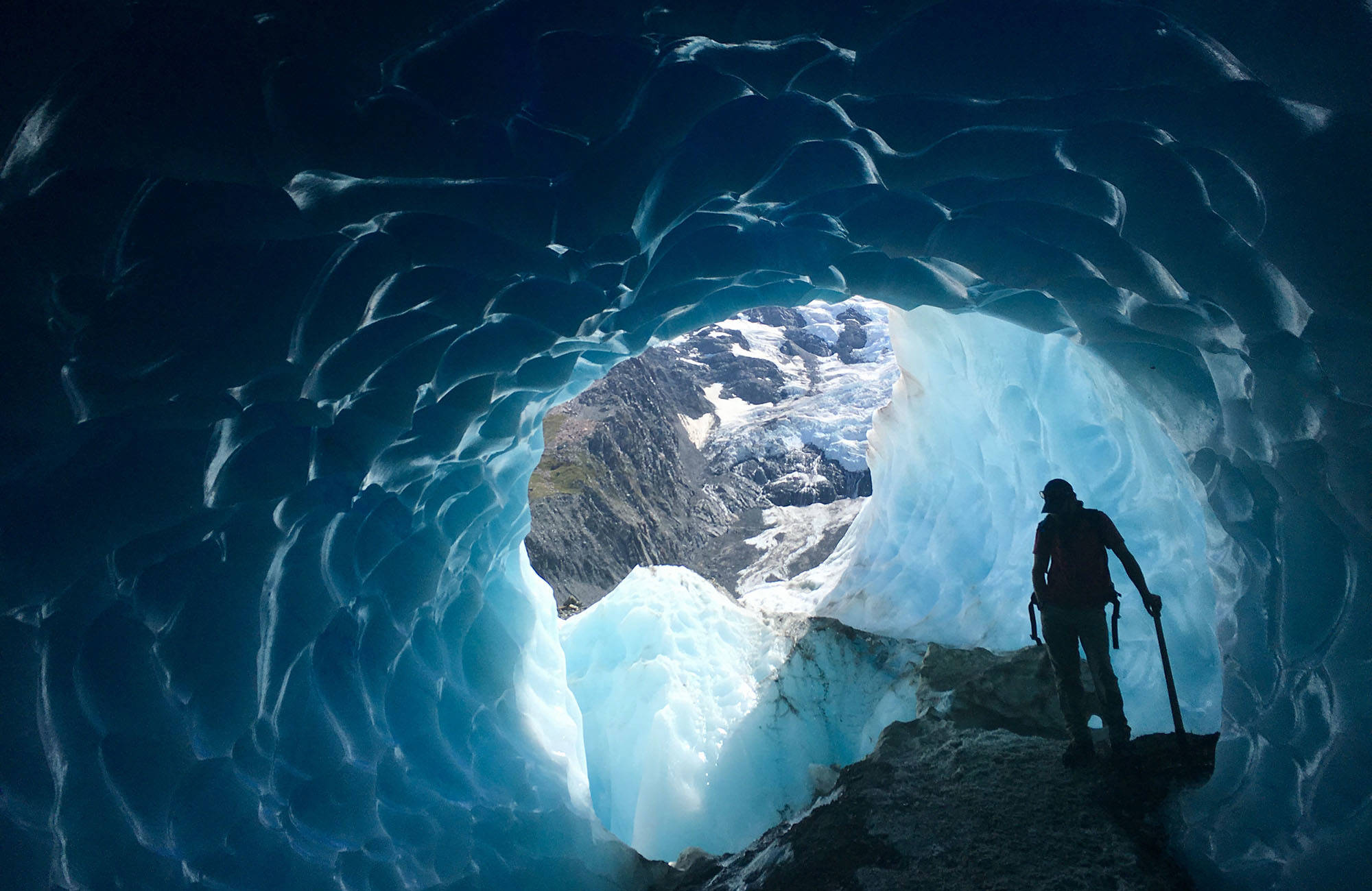 person  vandrar vid en glaciär i nya zeeland