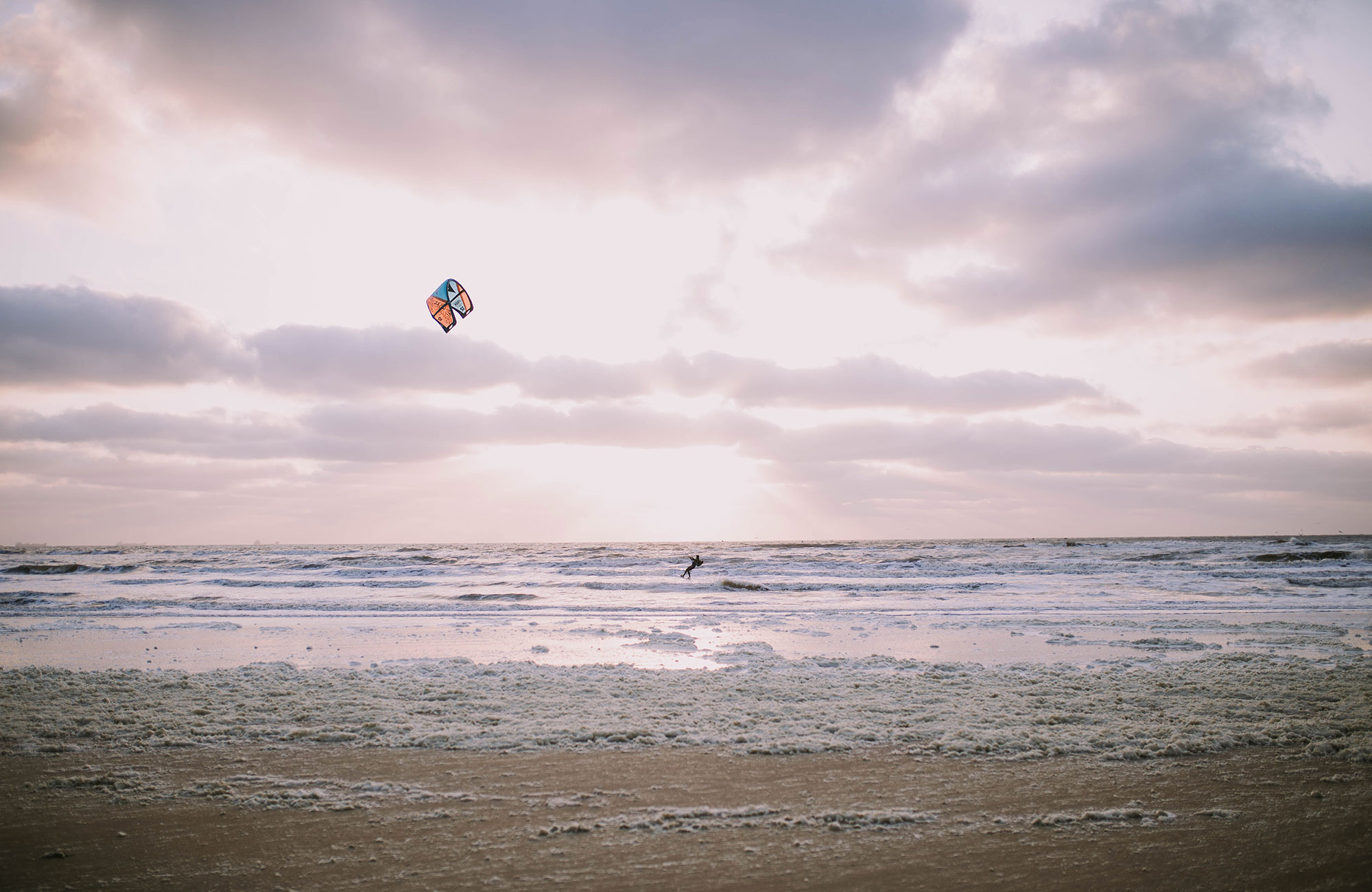 En strand och en person som provar på kitesurfing i Tanzania.