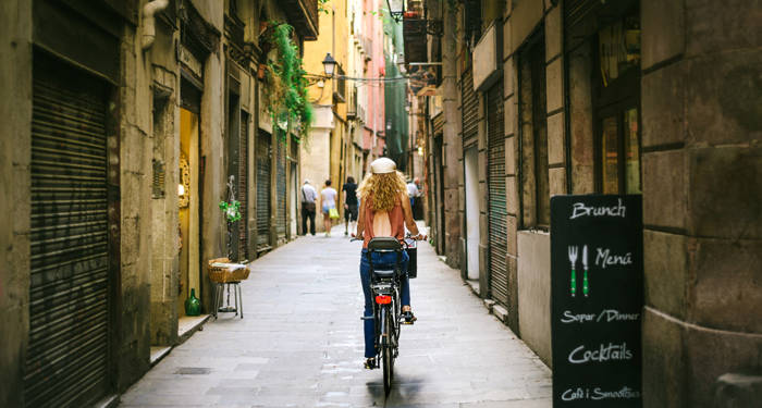 tjej som cyklar på en liten gata i barcelona i spanien