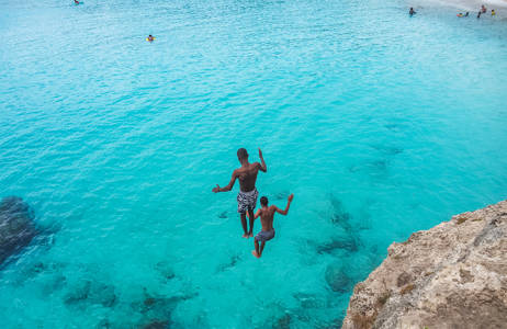 två killar hoppar i vattnet under en resa till karibien