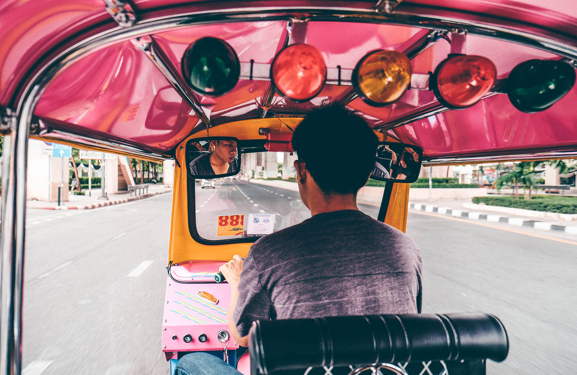 Man kör tuc tuc på en gata i Thailand.