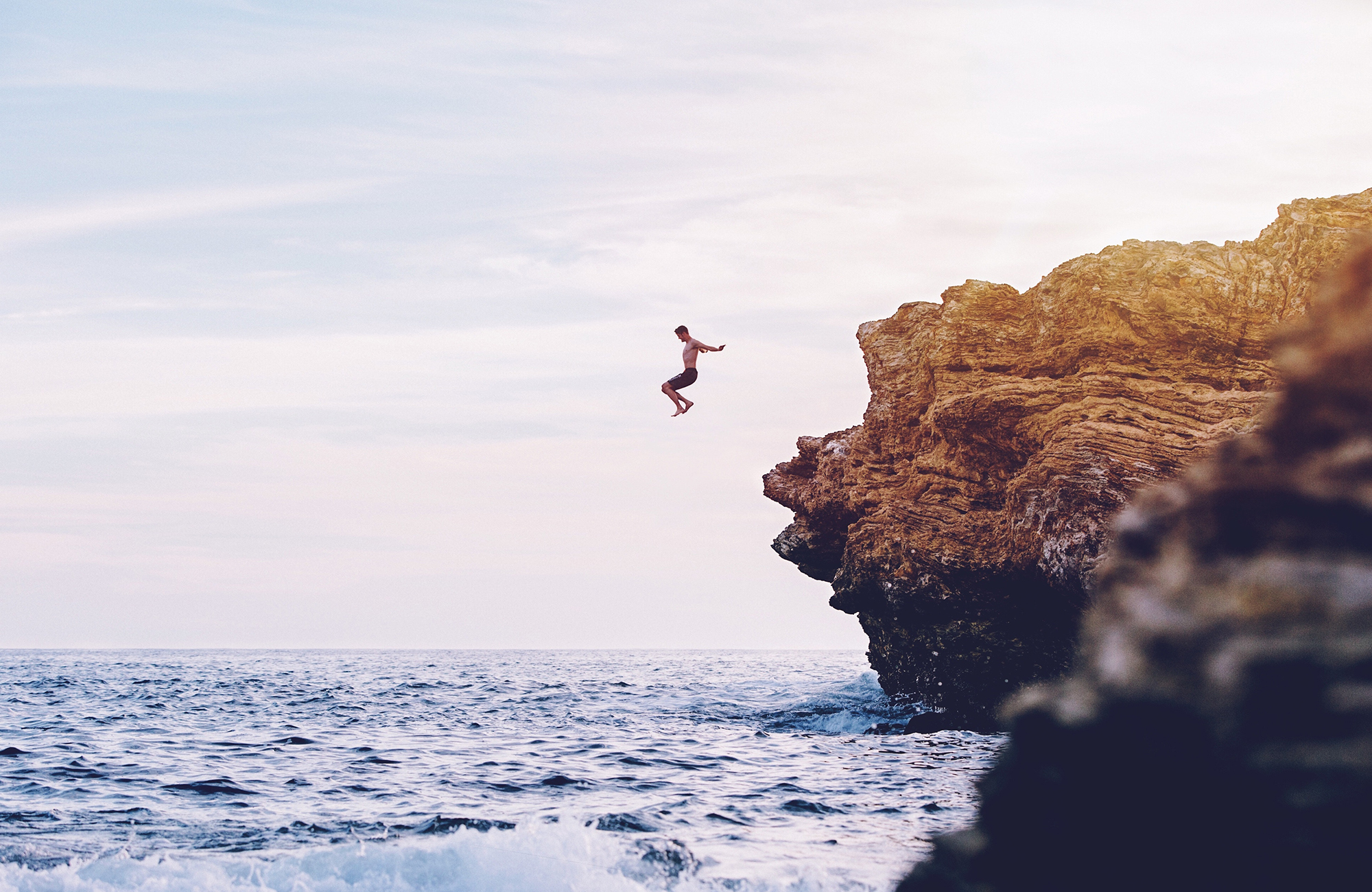 kille som hoppar i vattnet från en klippa
