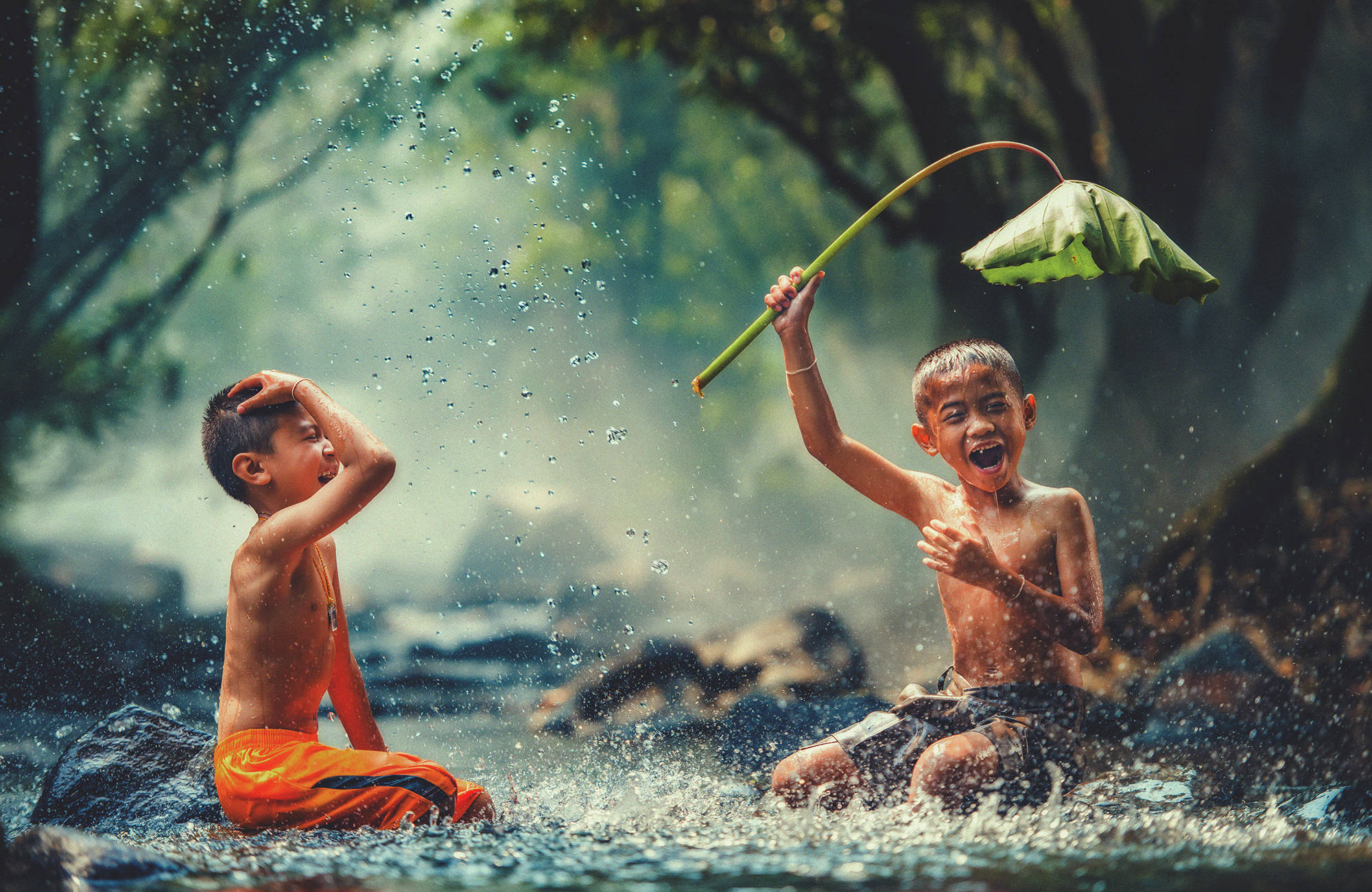 Två pojkar leker i vattnet i Kambodja.