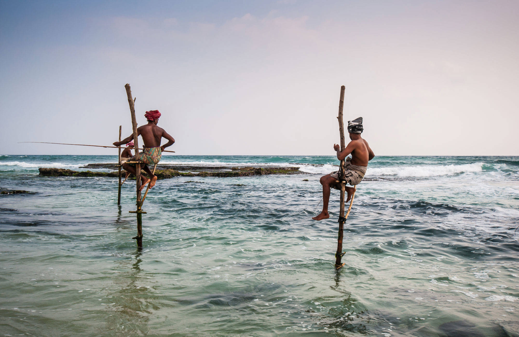Två män fiskar enligt lokal tradition på Sri Lanka