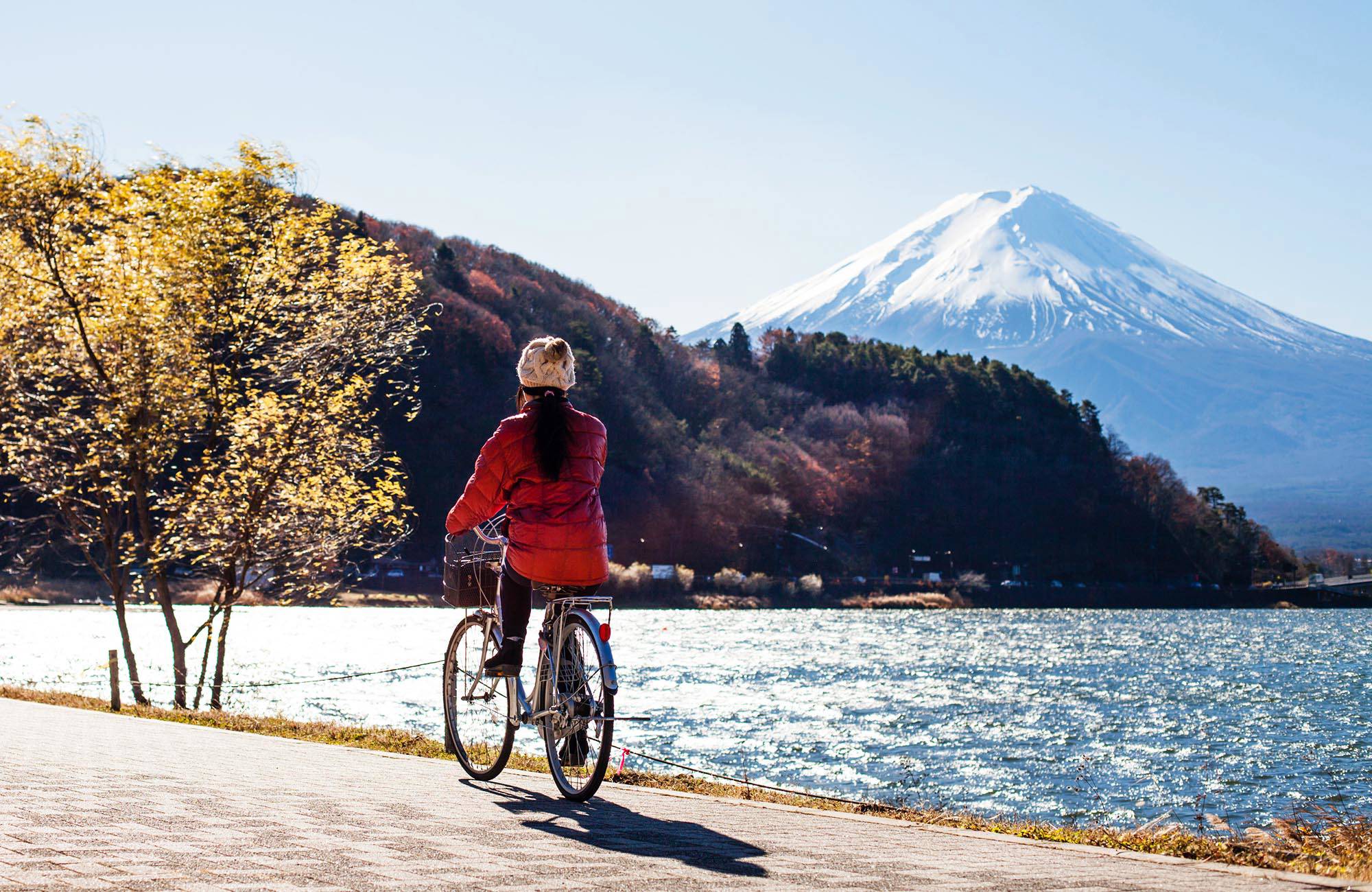 kvinna cyklar vid en sjö nedanför mount fuij