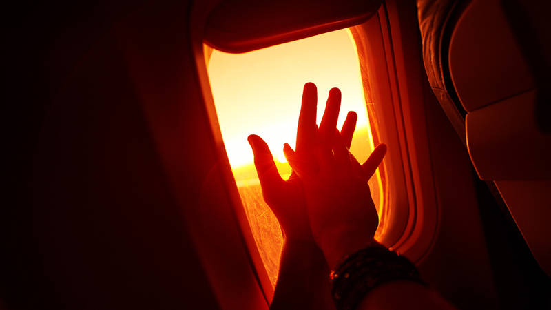 Två personer håller varandras hand på ett flygplan.