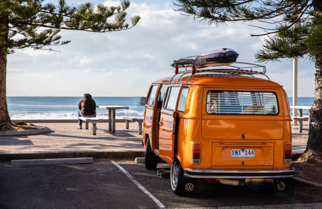 Gul van med surfbräda på taken vid en strand i Australien.