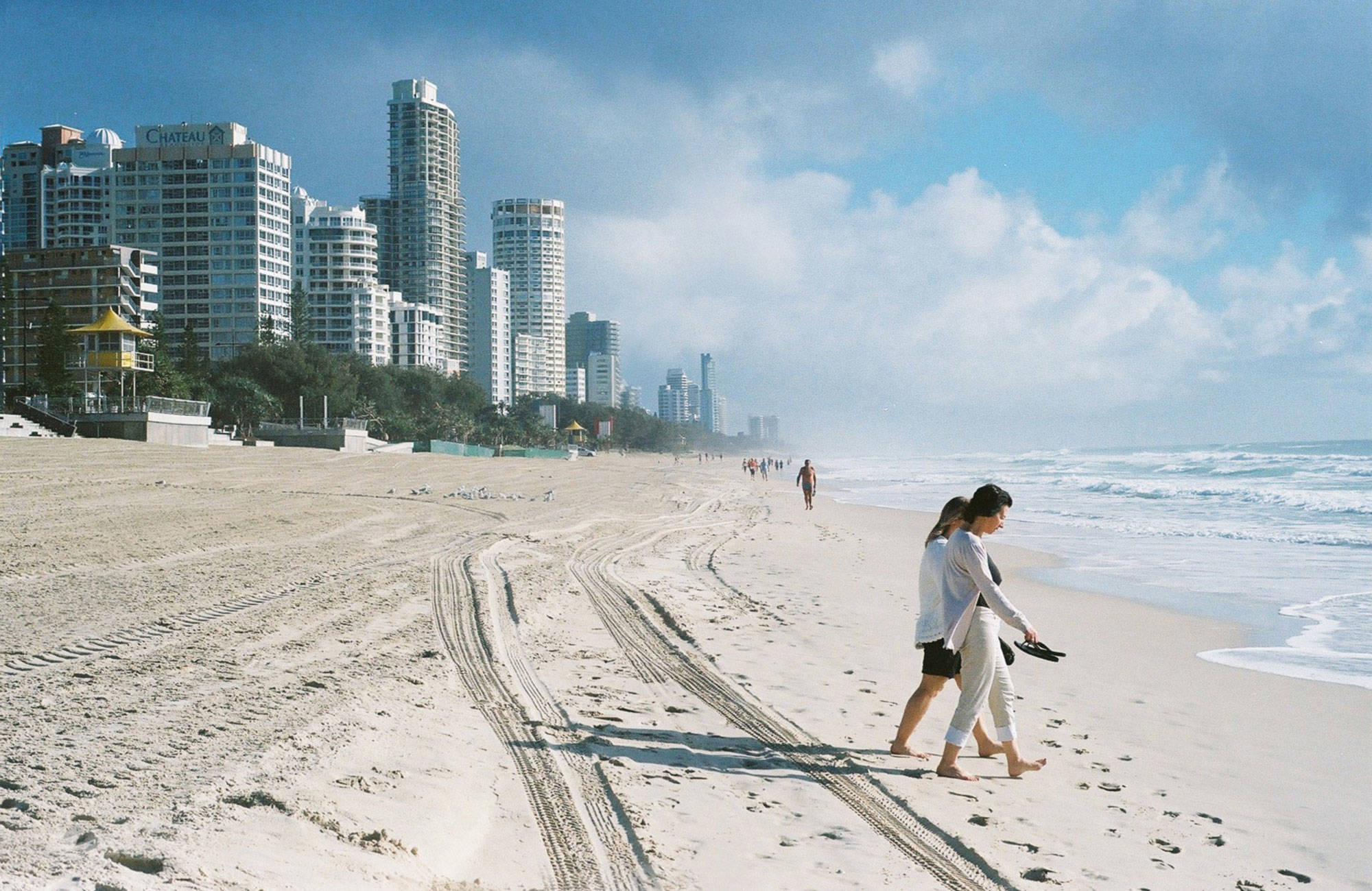 två personer promenerar på en strand på gold coast i australien