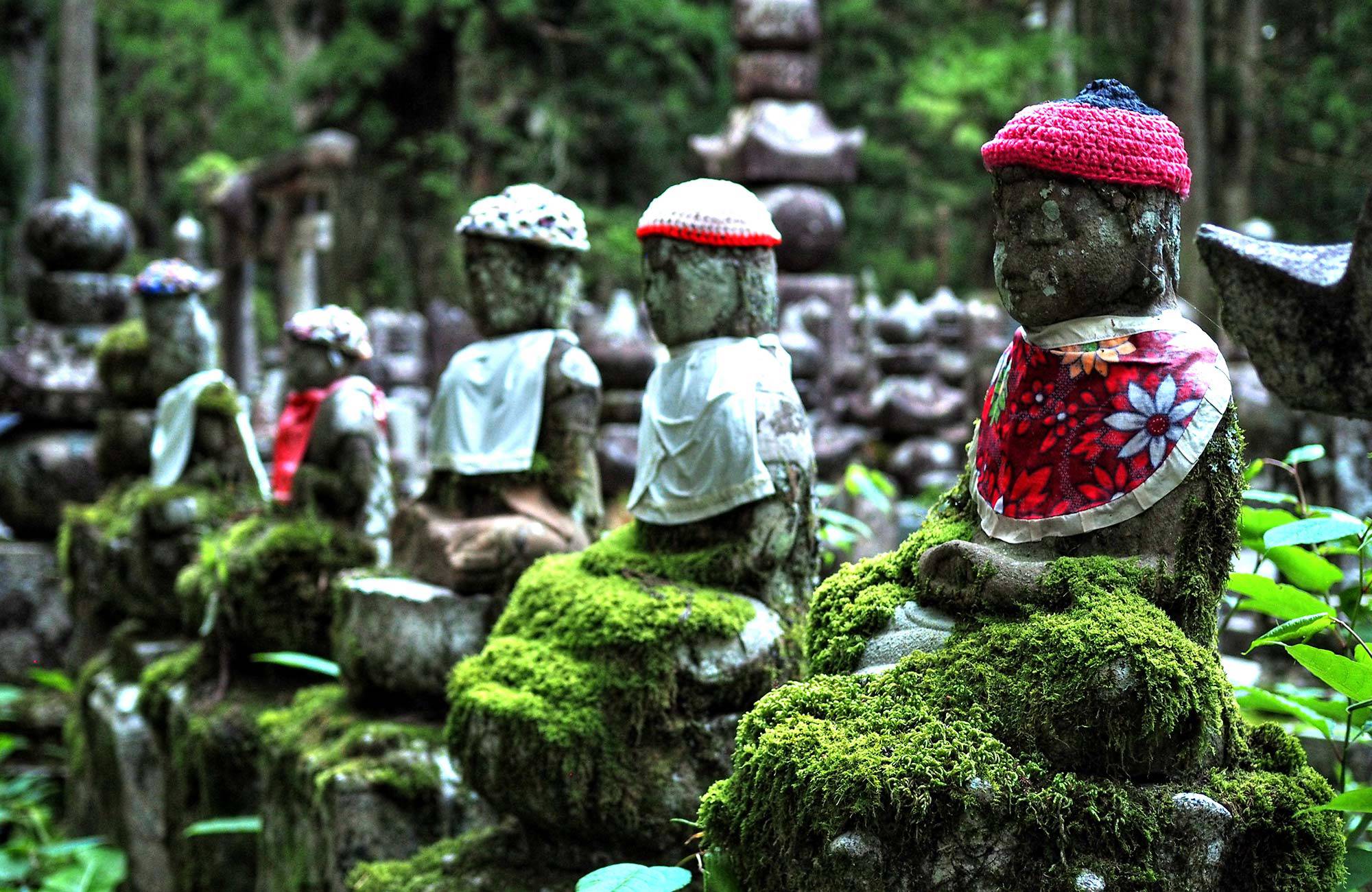 statyer med mossa på i ett tempelområde i japan