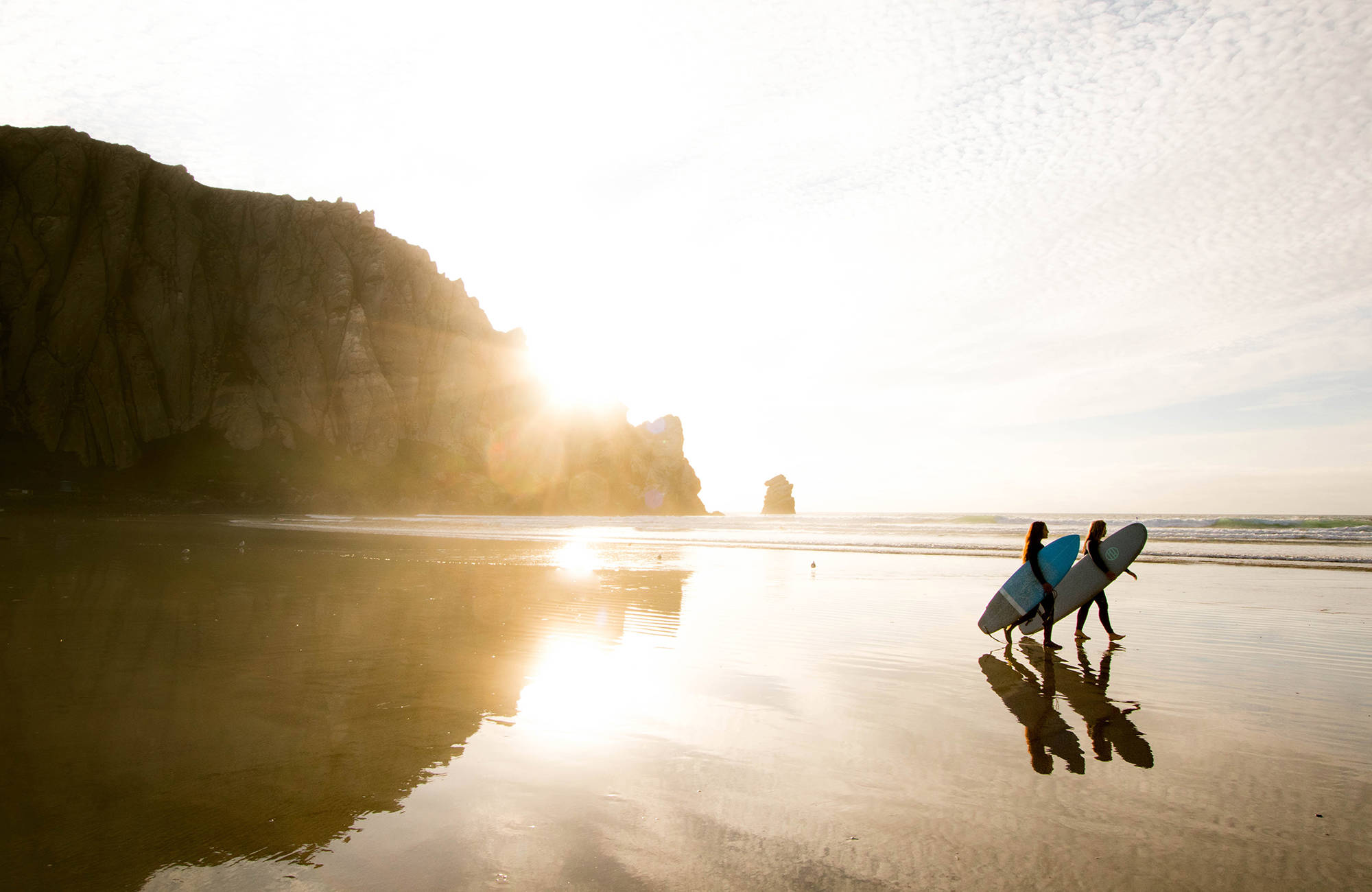 två studenter i san diego promenerar på strand med surfbrädor
