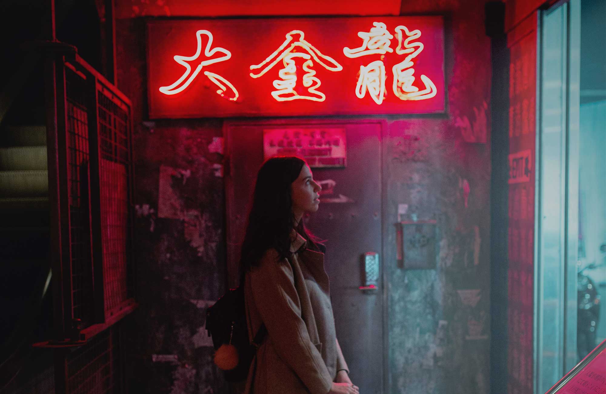 Kvinna i Tokyo framför en neonskylt.