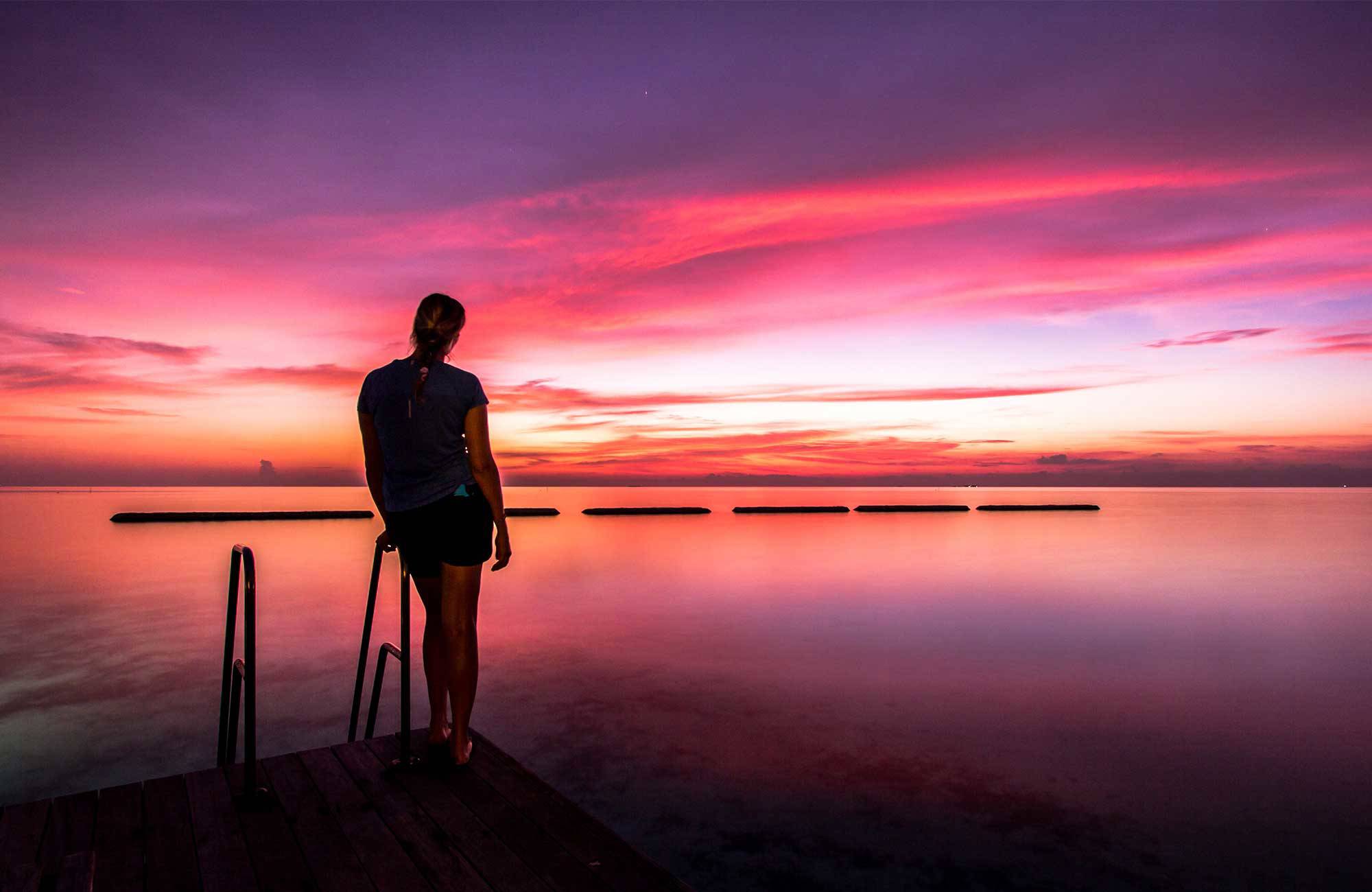 Kvinna ser över horisonten i solnedgången i Maldiverna.