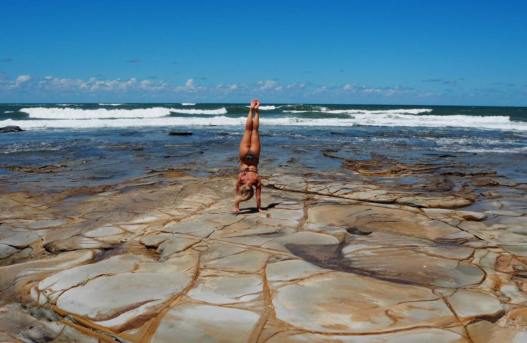 malin astår på händerna på en strand i australien