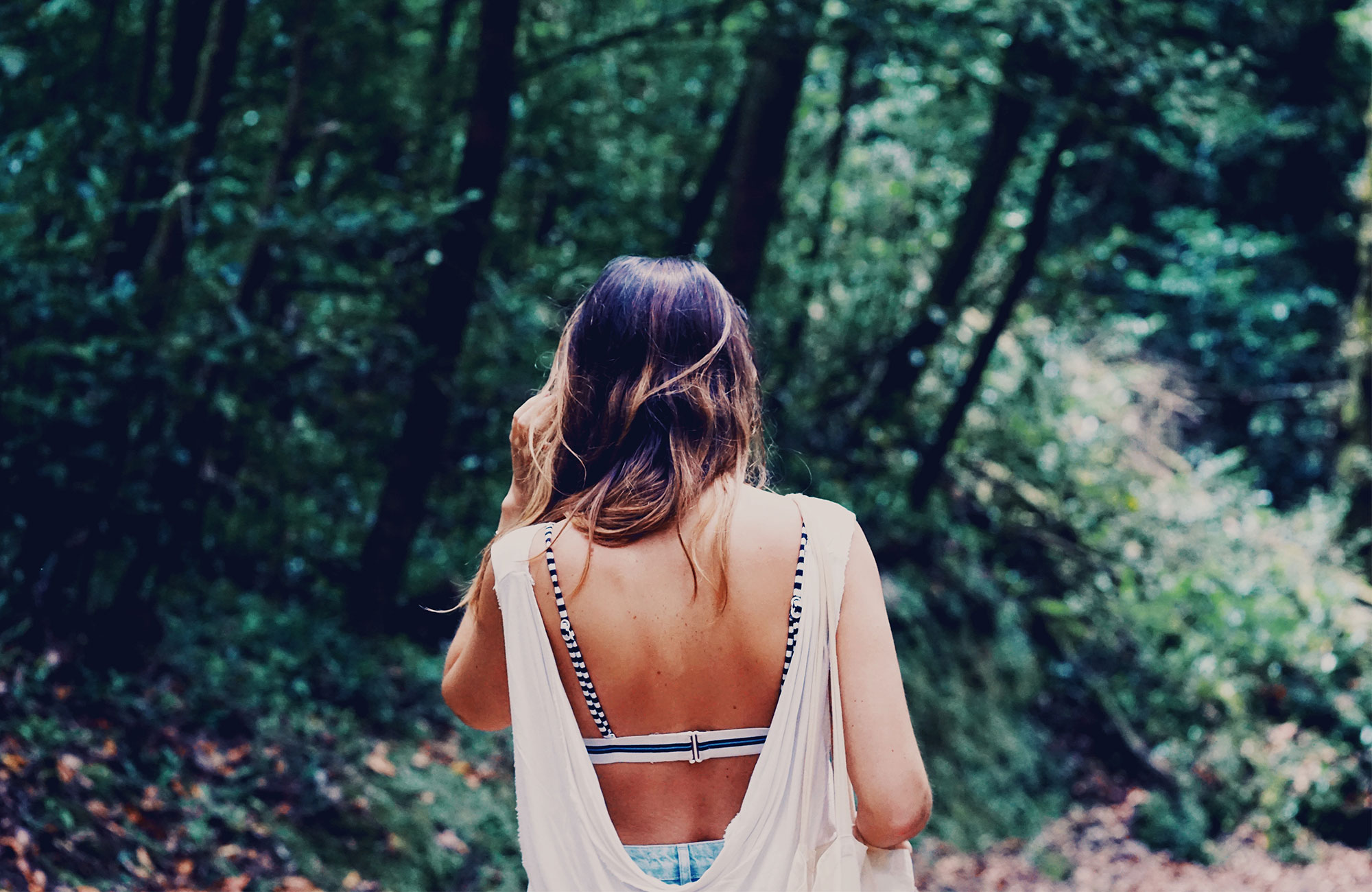 tjej med brunt hår som vandrar i en skog