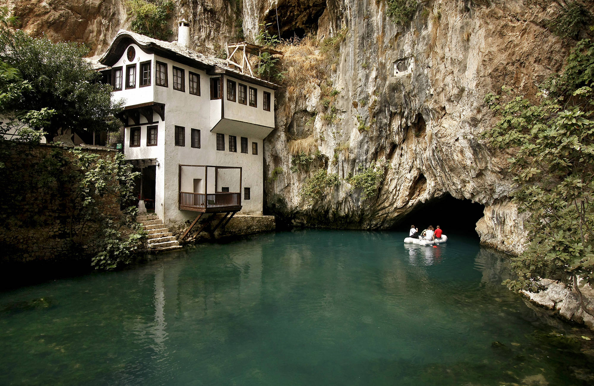 åk båt i floden på väg mot en grotta bredvid ett vitt hus i Bosnien-Hercegovina