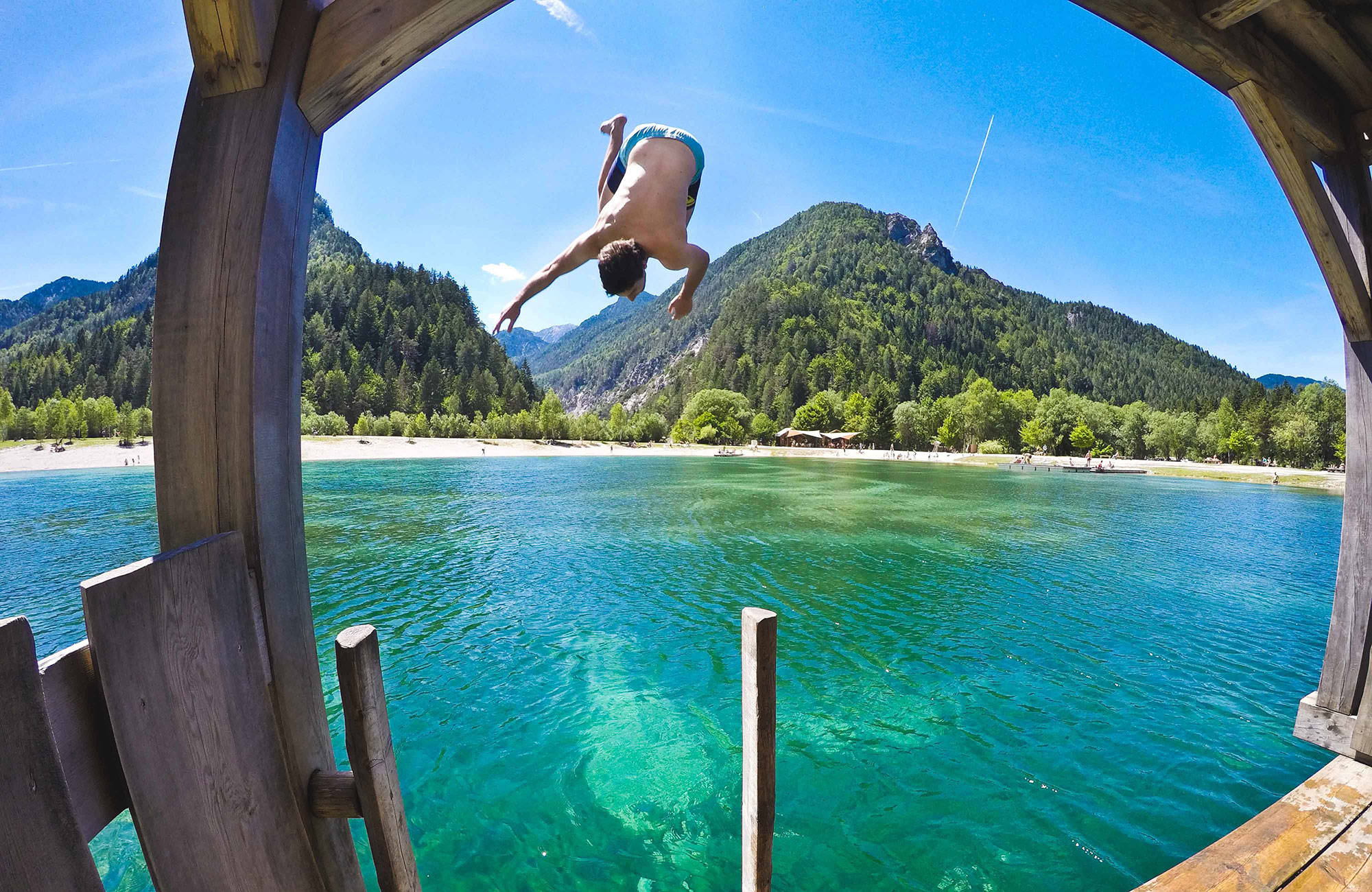 kille hoppar i vattnet i en sjö i slovenien