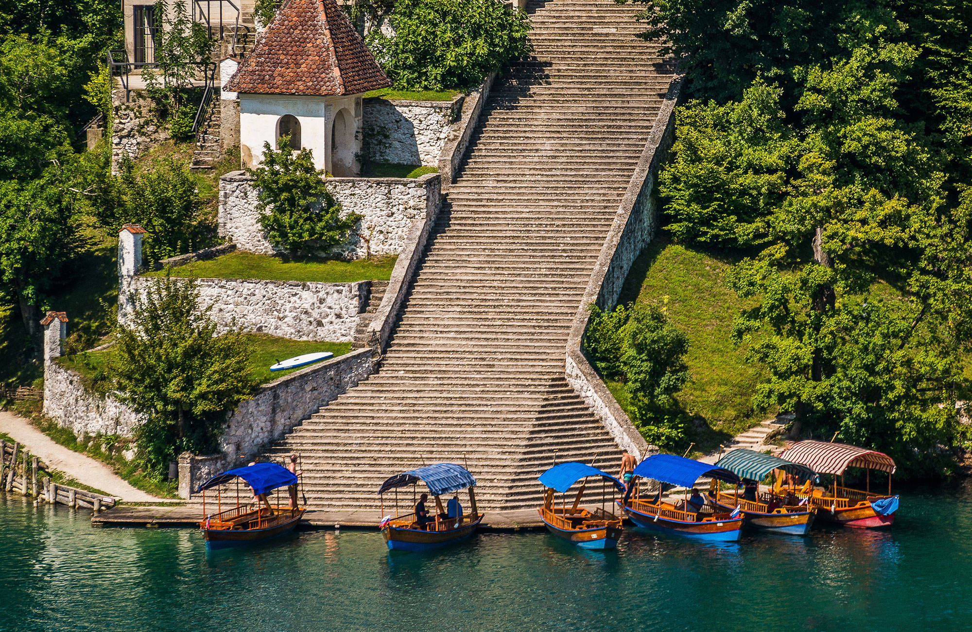 Båtar som stannar vid trappan upp till ön i Bled