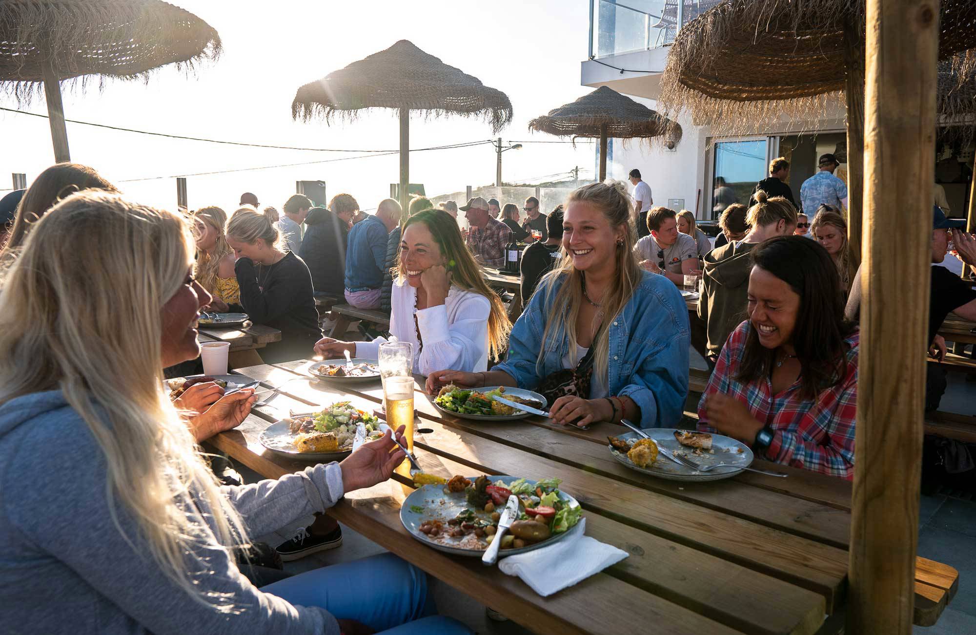 glada surfare äter middag under en rundresa i portugal