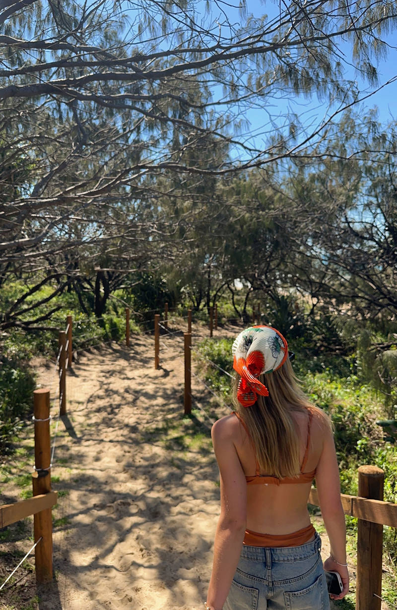 Girl walking og beach with red scarf on head