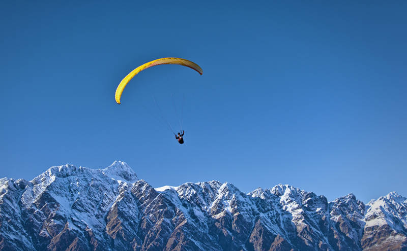 Paragliding over the snowcapped mountains near Queenstown in New Zealand