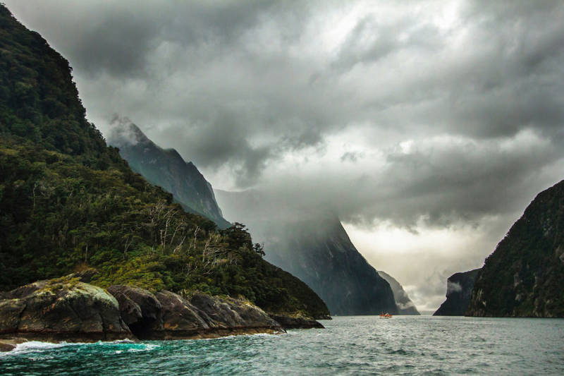 Heavy clouds hanging over the fjords of Millford Sound, with a boat in the distance