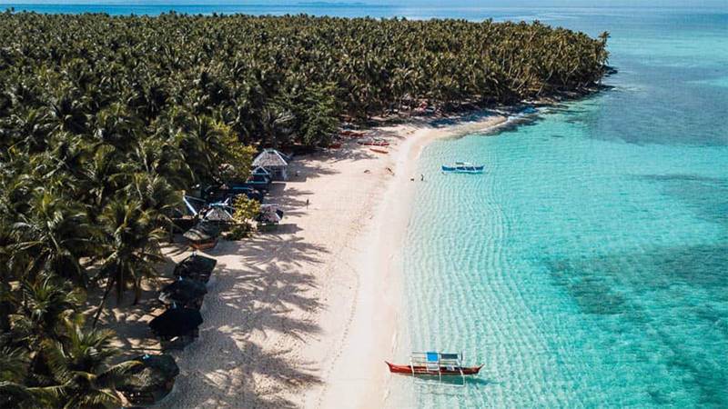 Pristine sandy beach with traditional boats in Siargao in the Philippines